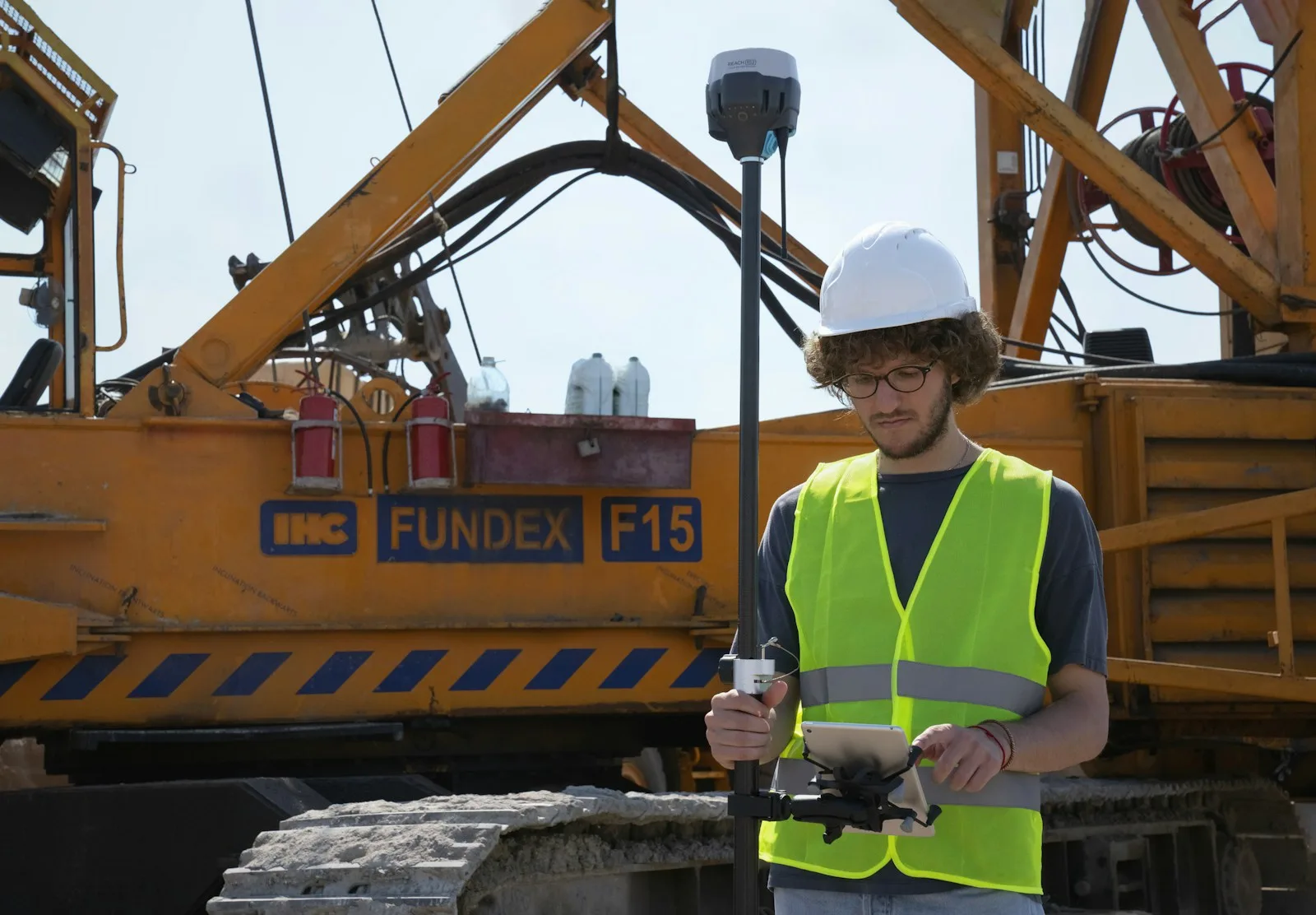 Field surveyor wearing a hard hat and using professional measuring equipment